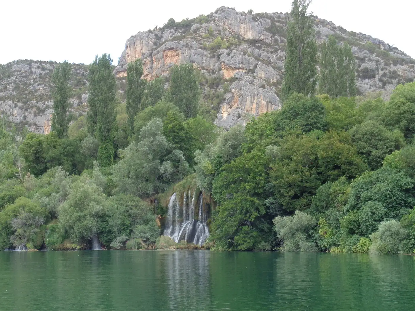 The low stepped barriers of Roški slap fanning across the Krka with the row of watermills on the bank